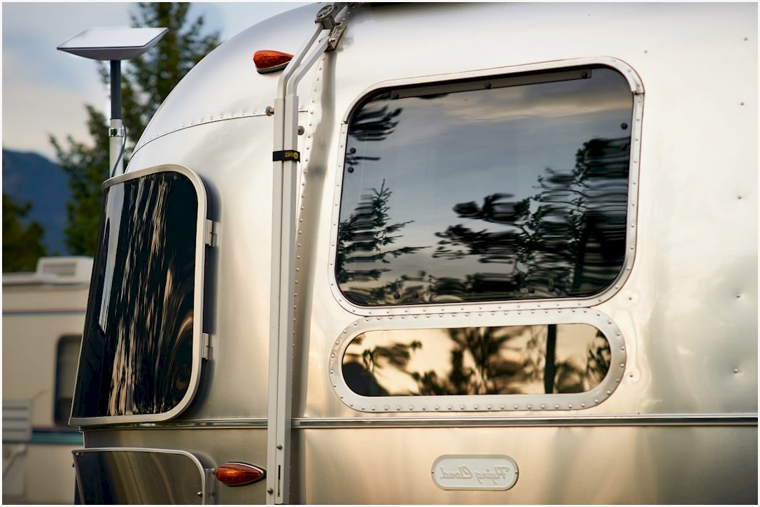 Silver airstream trailer reflecting trees and sky