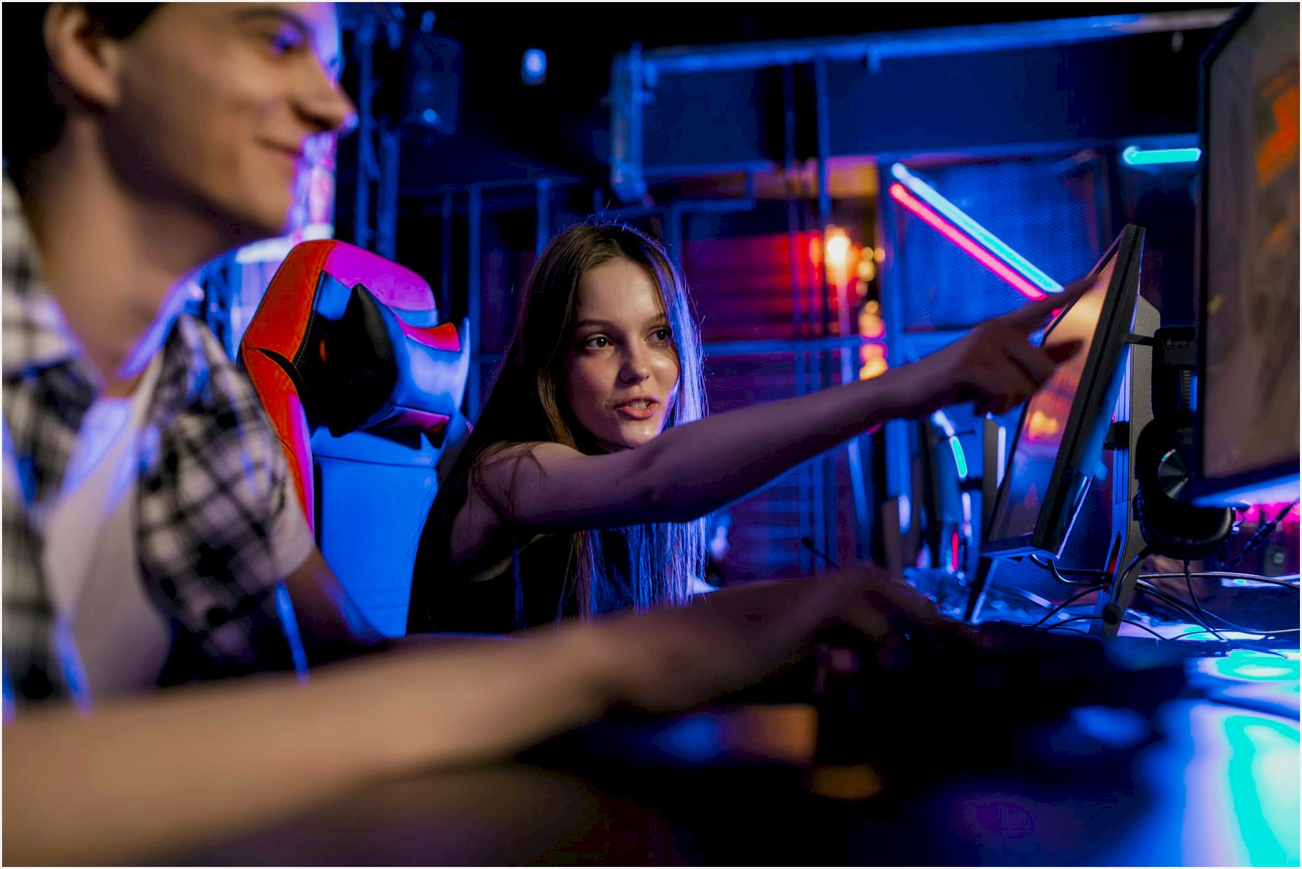 Teenagers engaging in a gaming session with illuminated monitors and vibrant LED lighting setup.