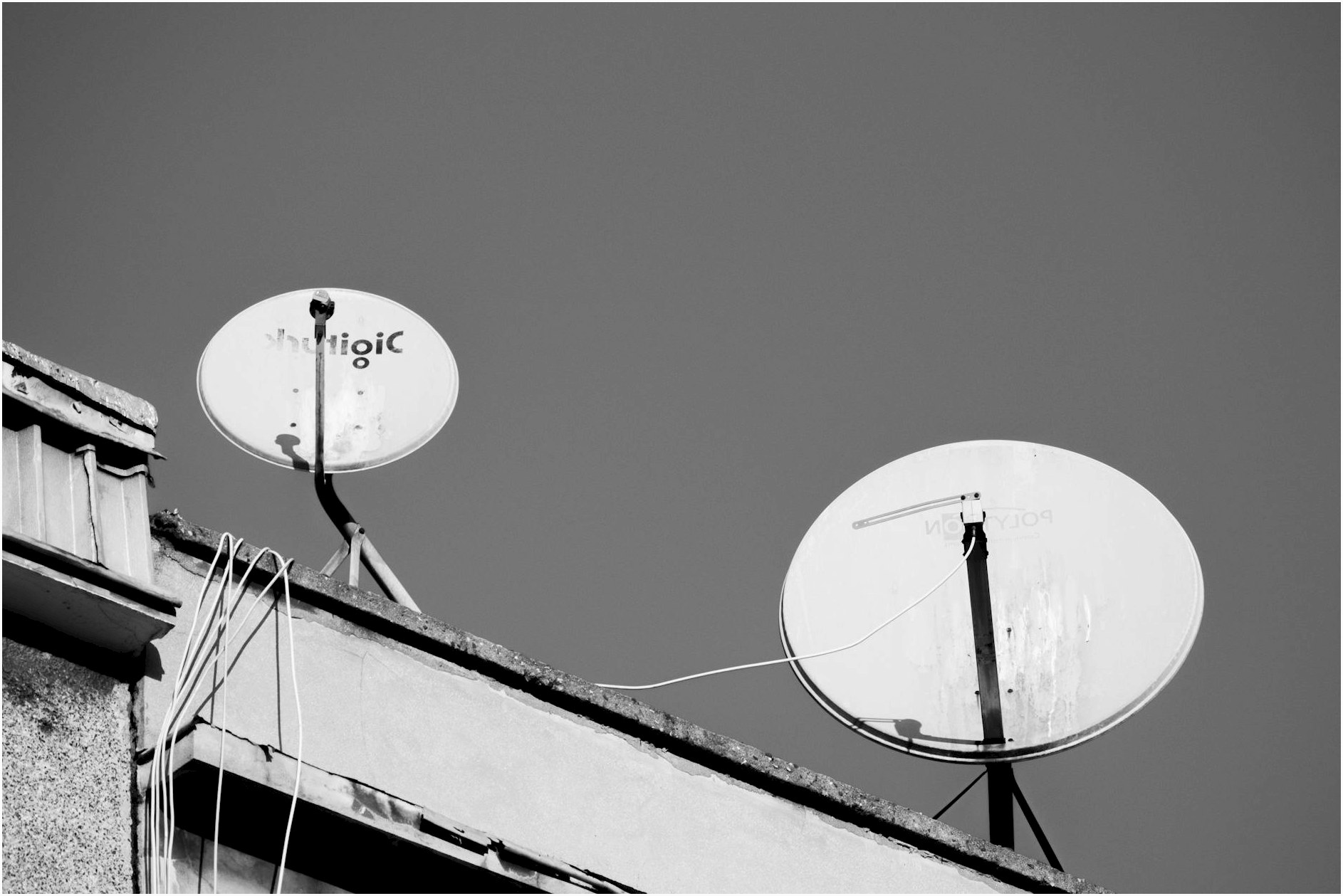 Monochrome image of two satellite dishes on a rooftop, representing communication technology.