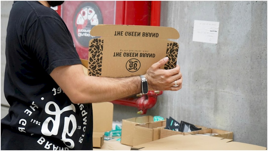 A man holding a cardboard box in front of a red fire hydrant