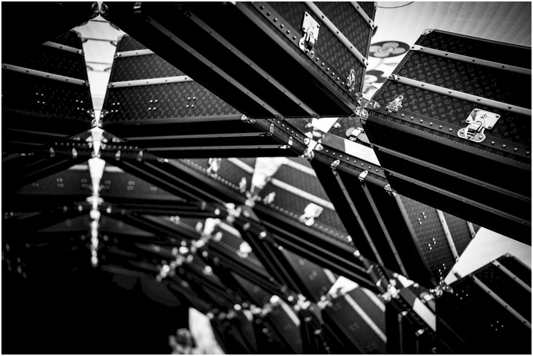 Black and white image shows many reflected suitcases.