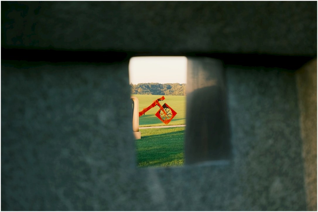 Orange abstract sculpture in a green field.