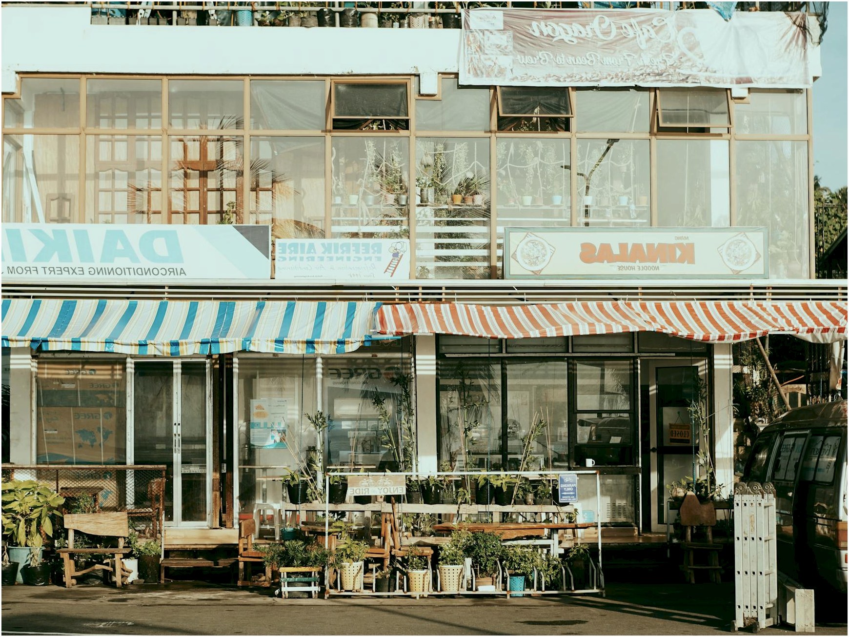 Charming street scene featuring local shops with colorful striped awnings and outdoor plants.